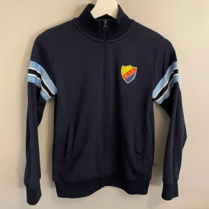 Djurgården tröja - Skit snygg djurgårds tröja. Fint skick förutom att det är ett litet hål i vänstra fickan, men inget som syns. Den är i stl 134/140 men passar en 150. Skriv om ni vill ha mer bilder!