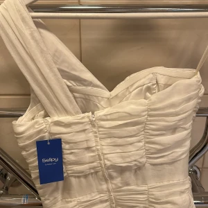 Vit klänning - Perfekt student klänning,  Har super fina detaljer och är som nu. Köpt på sellpy och har pris lappen kvar så har aldrig använt den. Jätte fin med dragkedja där bak. 