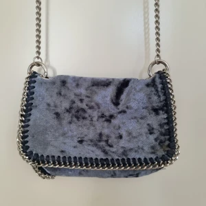 Blå sammetväska - Handväska i blå sammet med silverkedja. Fint skick. Litet innerfack med dragkedja.