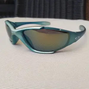 Ett par turkos/blå-grönmetallic solglasögon från Oakley. Glasen är utbytbara. Spegelglasen har några små nagg som inte märks när man bär dem (därav priset). Sjukt grymma solglasögon 