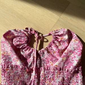 Klänning - Skitsnygg och väldigt somrig klänning, överdelen går att knyta som en rosett vid brösten eller runt halsen som en halterneck