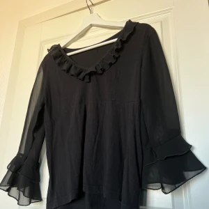 Svart volang topp - Skön, bekväm och unik svart topp med volanger från Cellbes. I väldigt bra skick, inga anmärkningar. Storlek 36, större i storleken. Beroende på hur du vill att den sitter, löst för en 36 och tajtare för en 38. Upphämtning i Malmö möjligt.