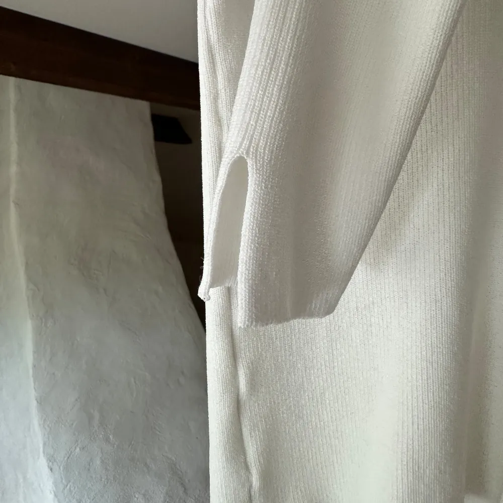 Långärmad vit ribbad tröja med slits vid ärmsluten. I mycket bra skick, det oanvänd ut.. Tröjor & Koftor.