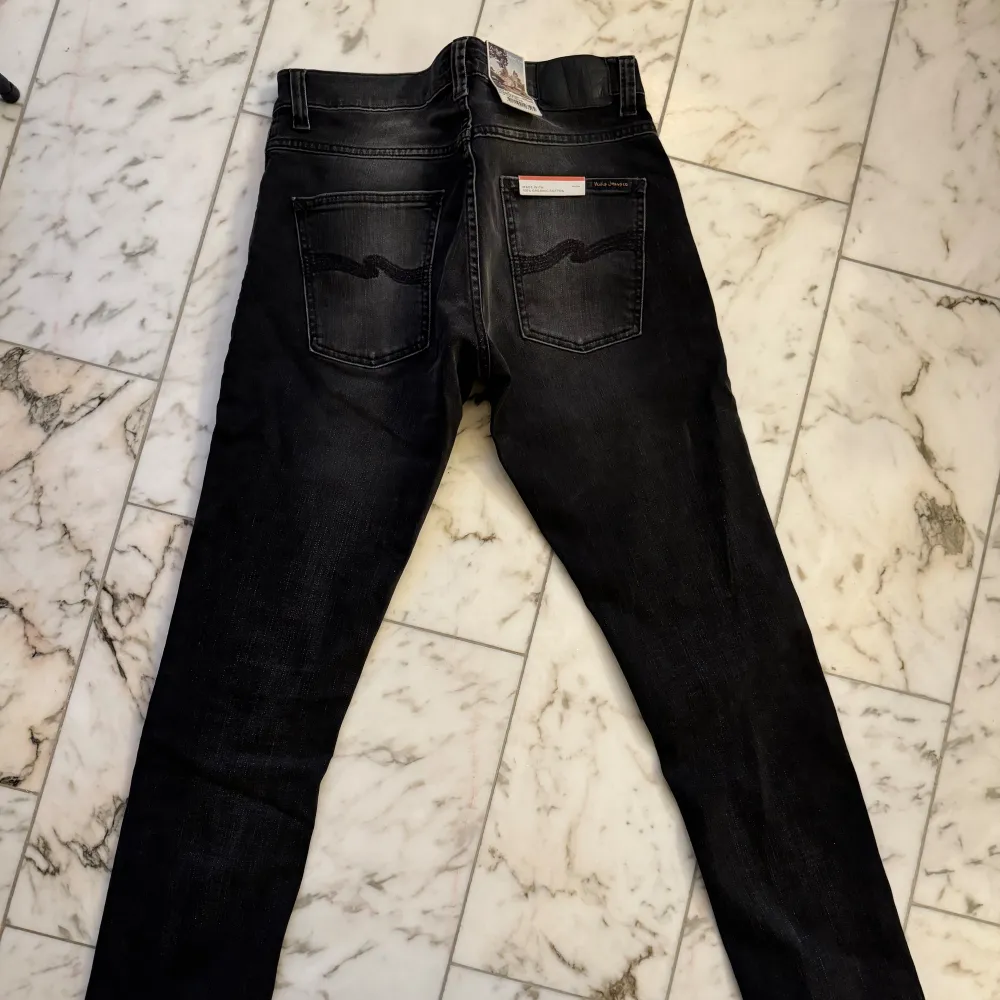 Helt nya svarta/gråa nudie jeans i modellen grim tim! Helt felfria och aldrig använda! Säljer pga fel storlek. Nypris är 1600kr. . Jeans & Byxor.