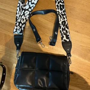 Väska  - Jätte fin väska från Nelly, två band följer med, de korta svarta är ordinarie band, de andra bandet är köpt vid sidan och alla saker är jätte fint skick 