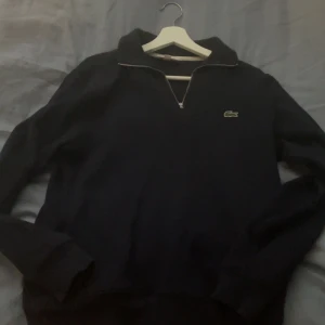 Lacoste Navy Blue Halfzip - Tjena, säljer denna Lacoste halfzippen då den inte kommer till användning längre. Den är i bra skick, inte så använd och har inga hål! Köpt i sommras på Åhlens City för ca 1 300kr, har tyvärr inget kvitto kvar så länge jag inte hittar det. 