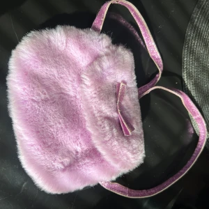 Blandade grejer - 1: Lila väska säljs för 20kr  2: Hjärtformade väska: väskan är fluffig och har en längre kedja säljs för 45kr  3: Katten säljs för 20kr  4: Vantarna med en katt på säljs för 60kr  5: Pumpen för ballonger säljs för 15kr  