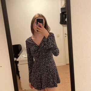 Blommig klänning - Svart klänning med lila blommor från NEW yorker. Går att knäppa upp vid bysten, säljer då jag inte använder den