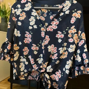 Blommig blus  - Blommig kroppad och kortärmad blus från bikbok som går att knyta åt i midjan.  Fint skick. 