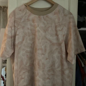 Topp/t-shirt - Topp/blus med tunt material. Supersnygg till vår/sommaren både vardags eller till fest. Använd fåtal gånger. Kan postas eller hämtas ut i Lund. Rosa/beige färg.