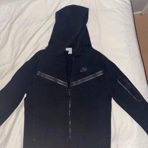 Nike Tech - Köpt på JD sport för 950 kr, den är i fint skick men har ett litet hål (bild 2) Kontakta om minsta fråga