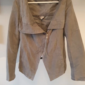 Grå bikerjacka i mockastil - Grå jacka i mockaimitation och bikermodell. Köpt för ca499 från H&M. Stretch på undersidan av ärmarna så går att ha en tunn stickad tröja under! 🤍