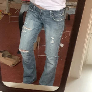 Lågmidjade jeans med detaljer - As snygga lågmidjade jeans som är Långa! Har silver detaljer fram o bak:) står ingen storlek men passar mig som brukar ha 36-38 i byxor.  Midjemått: ca 39 cm Innerbenslängden:84cm