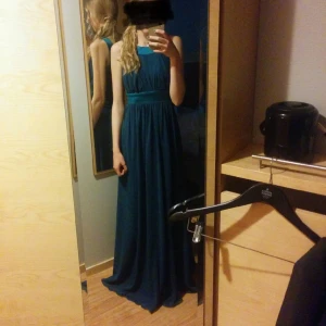 Lång balklänning - Mörkturkos i färgen, figursydd baktill, passform på 176cm utan klackar, gömd dragkedja på ena sidan, inbyggd padding. Nypris 2500, använd 2 gånger