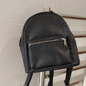 Liten svart ryggsäck med långa axelrämmar från H&M