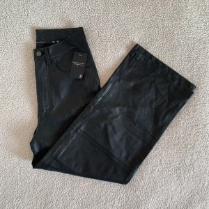 Lager 157 svarta läderbyxor i rakt utsvängd modell - Nya med tags kvar, utan anmärkningar.