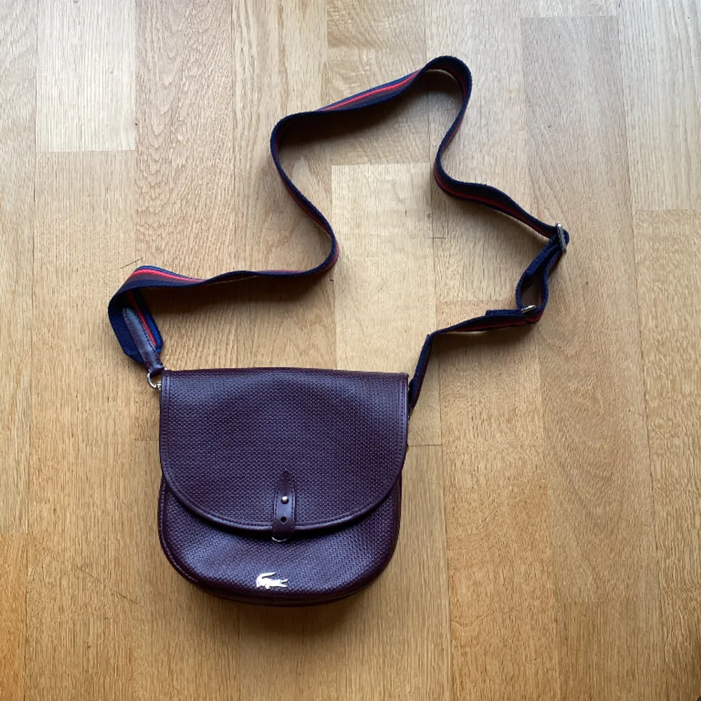 Säljer min superfina Lacoste väska då den inte längre används😔 mycket bra skick på utsidan och bra skick på insidan⭐️ mått ca 20x20 cm. Väskor.