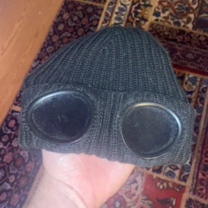 CP Company Mössa - Sjukt fet CP Company mössa med goggles, vänt glasen ut och in för jag föredrog det så men går att ändra. Köpte den på instagram för typ 3 år sen, men knappt använt den så den är dammig. Självklart äkta! Stor passform, skriv vid frågor!