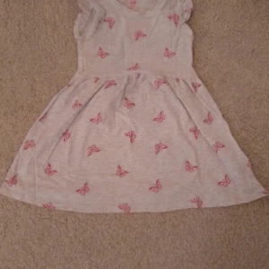 En perfekt bomulls klänning för tjejer mellan 2-4  - klänning är hel och fin. Den har också ett fint fjäril mönster. 