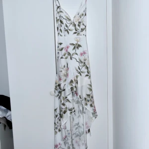 V-Neckline Dress - Blommönstrad volangklänning som har V-urringning med stavar.  Klänningen har reglerbara band i ryggen, är fodrad + underkjol samt dold dragkedja + hake i ryggen.  Använd 1 gång, säljer då den tyvärr är något för tajt i midjan på mig.  Nypris: 1695  