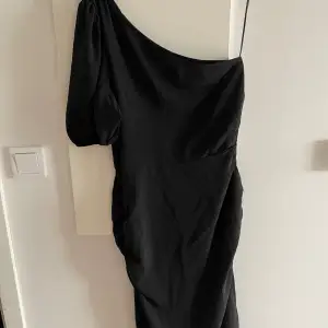 One shoulder Svart längre klänning med öppning vid en sidan 