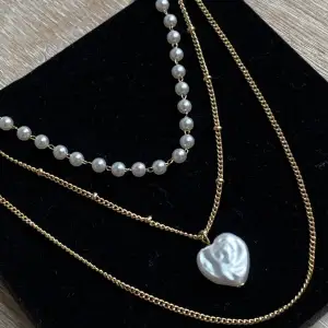 Halsband med med pärlor och hjärta i pärlemor. Kortaste kedjan är 41 cm lång, längsta är 52 cm lång. Justerings kedja är 7 cm lång. 