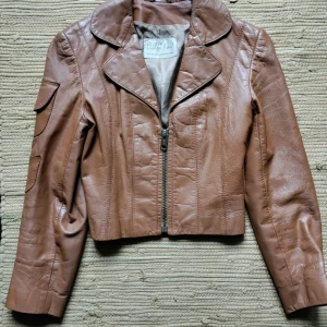 Läder jacka leather vintage ljusbrun 70 tan - Brun läder jacka Philippe Monet 70 tal Snygg croppad läder jacka 70 tal, ljusbrun!  Riktigt fin!    Armpits: 38  Sleeve: 54,5  Collar buttom :48  Shoulders: 40 