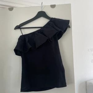 Svart topp - Fin svart ribbad långärmad topp med volang och fin skurning Storlek 158/164 men sitter som en XS/S