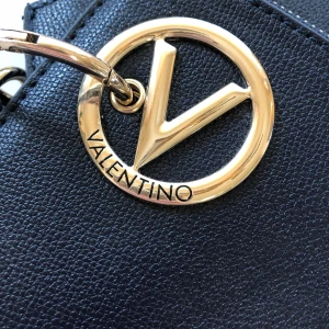 Kuvert väska Valentino  - Jätte fin i mörkt blå nästan svart med detaljer i Guld  Är två tunna väskor i en med en handledsrem.  Använd en gång på bröllop så toppen fint skick.  