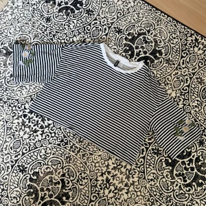 Randig croptop - Croppad top från H&M med broderade blommor på ärmarna. Använd endast ett fötal gånger, bra skick! Strl M