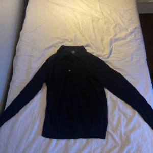 Uniqlo piketröja - En pikétröja i marinblå som är i merinoull från uniqlo som är i suveränt skick. Inga defekter alls. Sitter perfekt på mig som är ca 175cm lång. 500kr nypris!