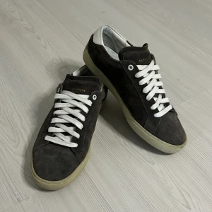 Saint Laurent SL/06 Skor - Tja säljer nu ett par gråa skor från Yves Saint Laurent i model SL/06! Nypris ~6000kr, mitt pris 2699kr. Skick 9.5/10 väldigt omhändertagna! Storlek 40.5 passar även 40/41. Priset är ej hugget i sten!