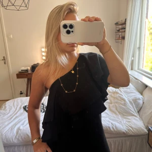 svart klänning med volangärm  - svart one shoulder klänning med volang ärm. storlek 34 från top secret