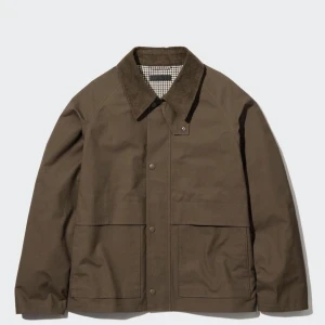 Brun jacka med krage - En brun jacka med krage och knappar framtill. Jackan har två stora fickor och en rutigt mönstrad insida.