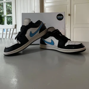 AIR JORDAN 1 LOW BLACK UNIVERSITY BLUE WHITE - Tja, nu är mina Jordans ute då de blivit försmå i storlek. Skorna är i storlek 41 men passar även fötter i 42. Väldigt bra sick men lite slitningar, helhet så är skorna i 8/10 i sick. Väldigt fina och sköna !!   (Ny pris kostar skorna 2700 kr! )