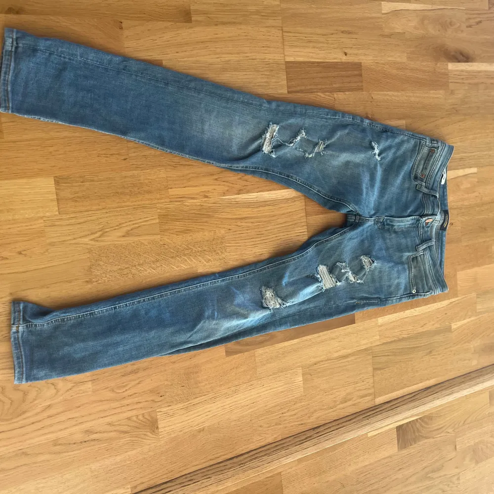 Ett par blå jeans från jack&jones med slitningar på framsidan. Jeansen har en smal passform och är i storlek 30/32. De har en klassisk femficksdesign och är tillverkade i denim.. Jeans & Byxor.