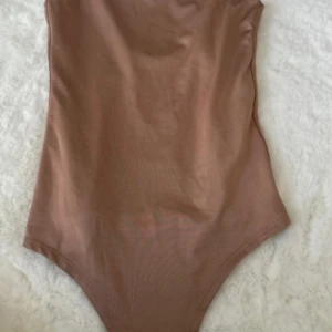 Brun baddräkt - En brun baddräkt med enkel design. Baddräkten har en öppen rygg och är ärmlös.