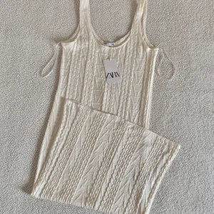 ZARA kabelstickad vit mysig lång klänning - Så himla mysig lång krämvit kabelstickad / jacquard klänning från ZARA. Otroligt mjukt och mysigt material. Perfekt för såväl vår som sena sommarkvällar. Sitter avslappnat på kroppen, se gärna produktbilderna. ❣️