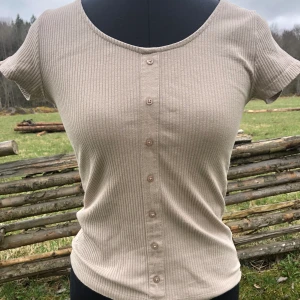 Beige top - Fin beige top med dekorations knappar. Den är använd några gånger. Den är i relativt bra skick.