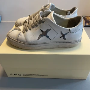 Axel Arigato skor - Säljer dessa jättefina Axel arigato skorna med fåglar på! Är ganska använda och lite utslitna men de funkar ändå bra att använda❤️Skorna levereras även i originalkartongen.