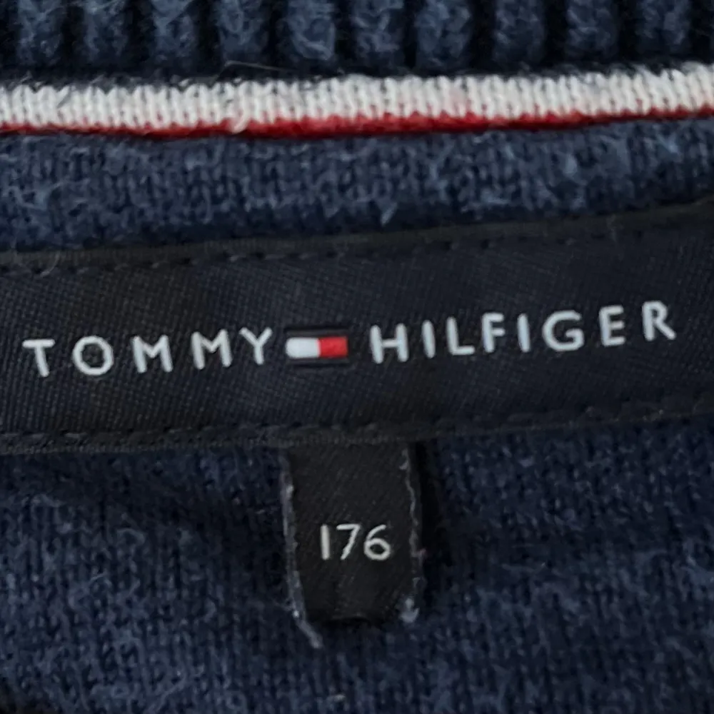 Stickad Tommy Hilfiger tröja i blått med vita och röda detaljer. Storleken som står på tröjan är 176 men stämmer ej, motsvarar mer en 164.. Tröjor & Koftor.