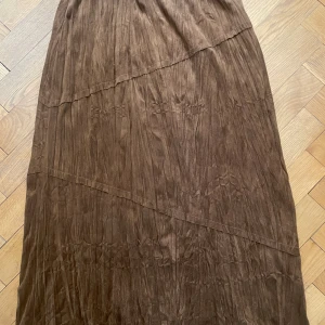 Långkjol fuskmocka - Ljusbrun, skråddsydd, vid långkjol med elastisk linning i mjuk fuskmocka (polyester). Tvättas i 30 grader. Mycket fint skick!