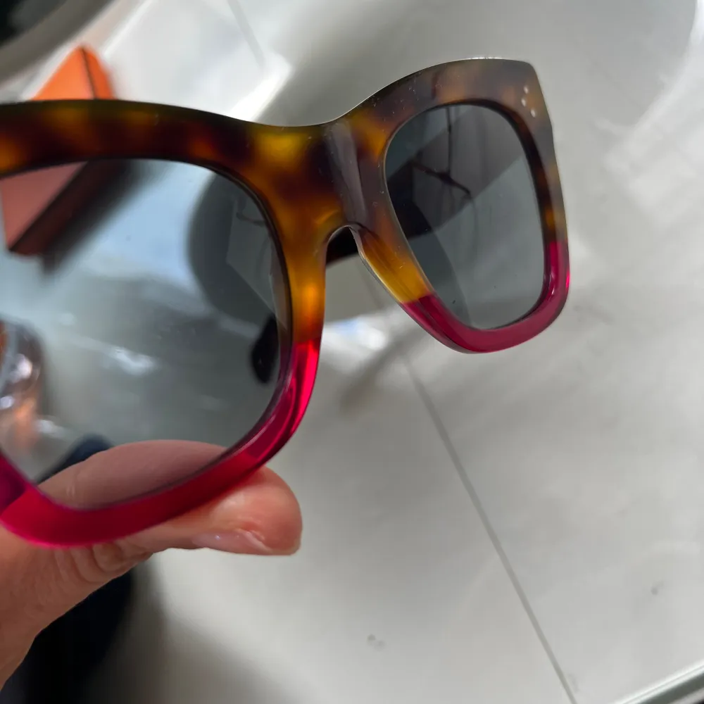 Klassiska solglasögon från Celine med two-toned frame. Soft cover följer med. Modell: CL41090/s Lens width: 50mm Bridge size: 22mm De är använda och finns obetydliga repor här och där som jag verkligen försökte att fånga . Nypris: 4379 kr. Accessoarer.