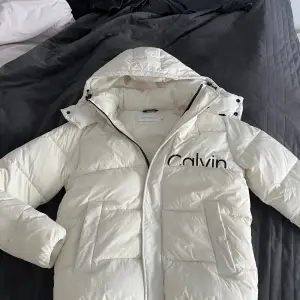 En vinterjacka från Calvin Klein Jeans. Färgen är äggvit. Storlek L  Två sidofickor en inneficka 
