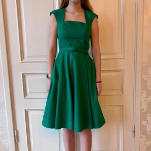 Grön klänning, Emmy Design - Grön klänning. Storlek 40. Lite trådig där skärpet drar mot tyget, syns ej på avstånd. Modellen på bilden är 173 cm och har storlek 38 i de flesta andra kläder. Aldrig använd. Vi har lagt ner vår klänningsbutik och säljer ut. Ny pris är 2000-3000kr