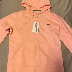 Helt ny aldrig använd Lacoste hoodie i rosa. Skit snygg nu på våren och sommaren den är i storlek S men kan passa M med. 1:1 med tags och allt.