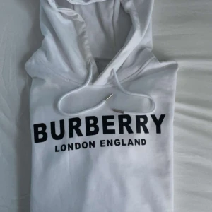 Vit Burberry Hoodie - Helt ny burberry hoodie nästan helt oanvänt och fräsch. Jätteskön material men storleken är mycket större än vad det står. De xs men sitter som M. Kontakta för mer information.