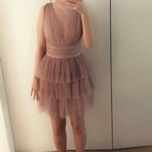 Nicowa volangklänning - Säljer min fina Nicowas beige/rosa volangklänning. Har använts bara två gånger. En liten defekt i fållen. Syns inte i bruk. Har köpt för 2425 kr. Säljer för 1630kr. Priset kan diskuteras.  140€=1630kr