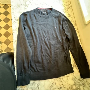 Mörkblå Tommy Hilfiger Flag Logo Tröja  - En Tommy hilfiger flag logo tröja i storlek S. Tröjan har använts en del men ser ändå relativt ny ut. Tröjan är aningen tjockare och fungerar perfekt ovan på en skjorta eller liknande. Tröjan är mörkblå och detaljerna syns tydligt på tröjan.  