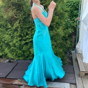 Långklänning  - Drömigaste blå/turkos lång klänning med unika insydda gröna pärlor runt v-ringningen & snören som man knyter bakom nacken. Jättefin i ryggen! Perfekt till balen, eller om man ska vara finklädd🩵 insydda pads i brösten! Har endast använt den en gång🫶🏼 